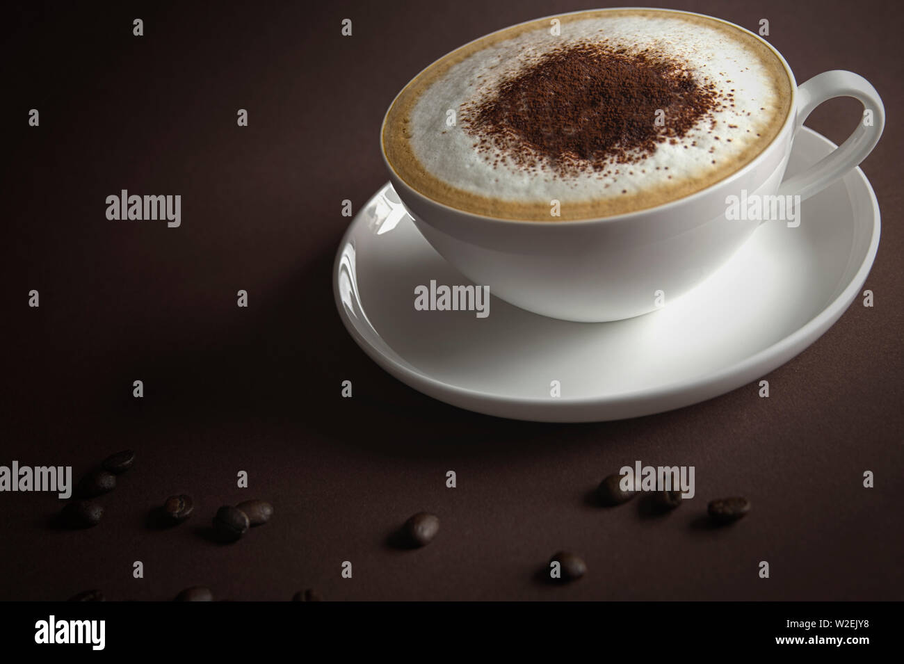 cup of cappuccino with cream and coffee beans on brown background Stock Photo