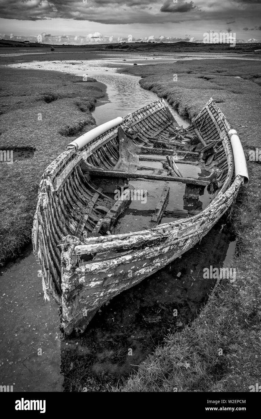 An old broken wreck of a fishing boat left on the marsh inlet to the sea.  This was taken in County Mayo Ireland. Stock Photo