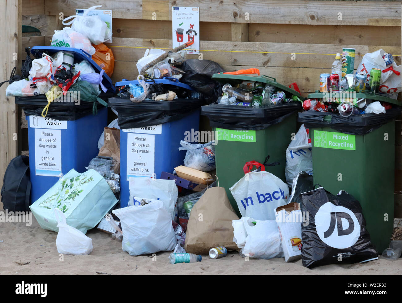 Overflowing recycling wheelie bins awaiting collection on the beach ...