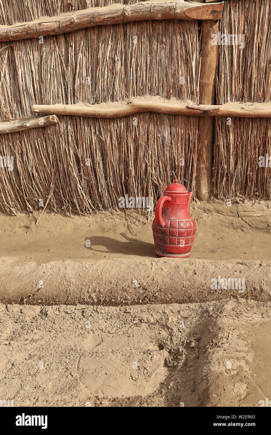 Red plastic pitcher-Uyghur reeds and mud hut yard. Taklamakan Desert-Xinjiang-China-0293 Stock Photo