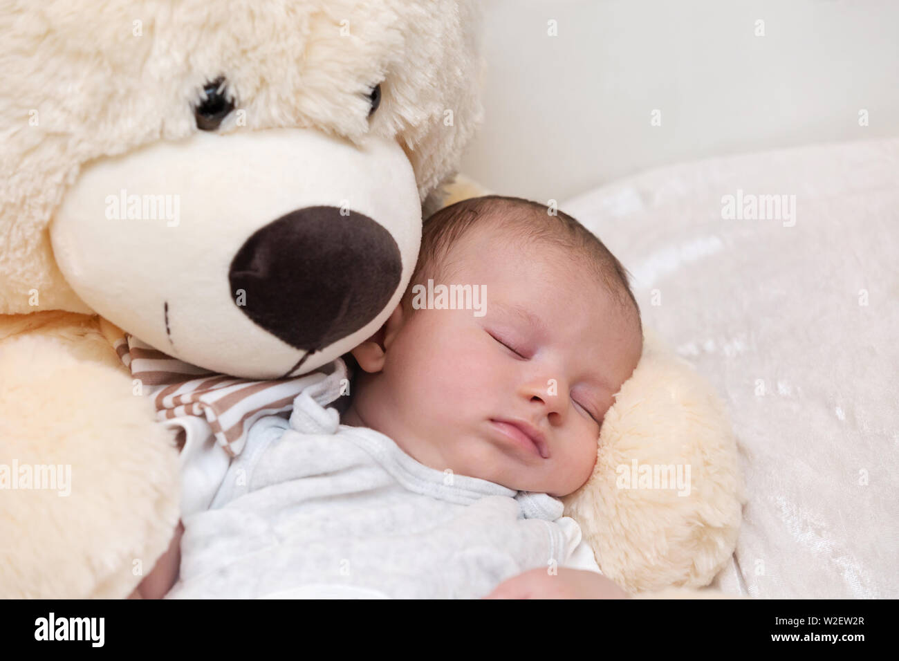Peaceful newborn sleeping with giant fluffy teddy bear Stock Photo