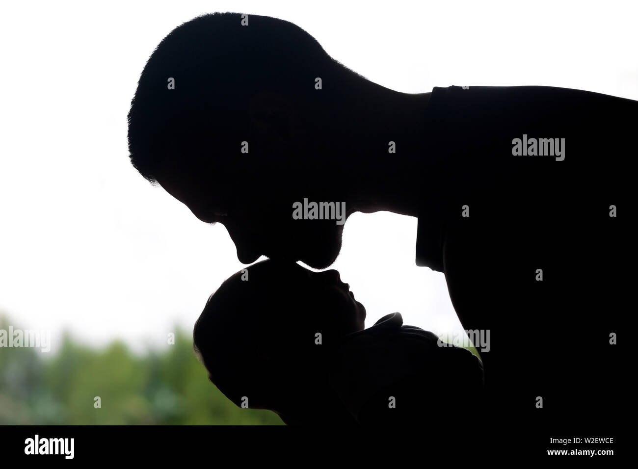 Silhouette of new father kissing newborn child on the forehead Stock Photo