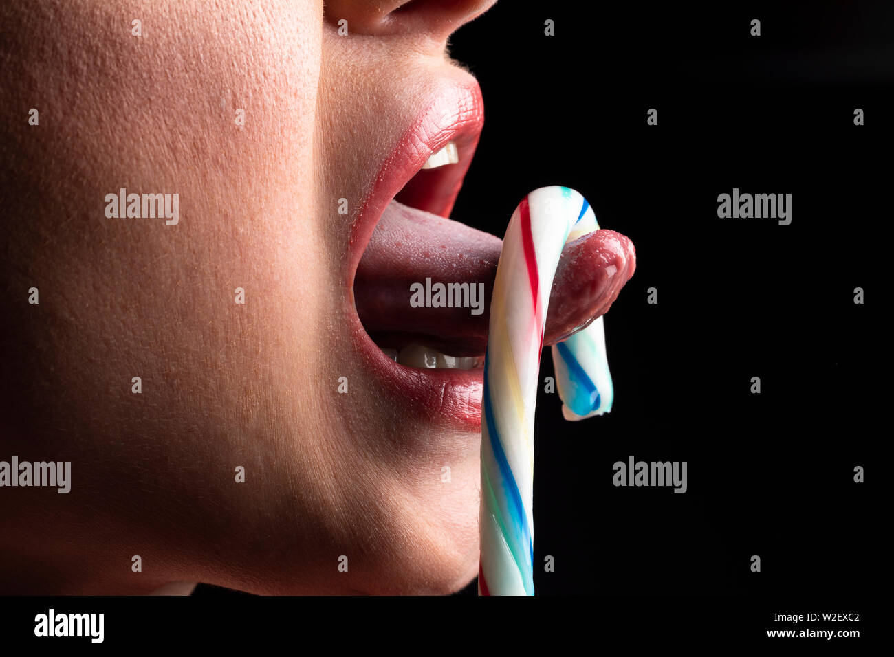 Woman licking lollypop, black isolated Stock Photo