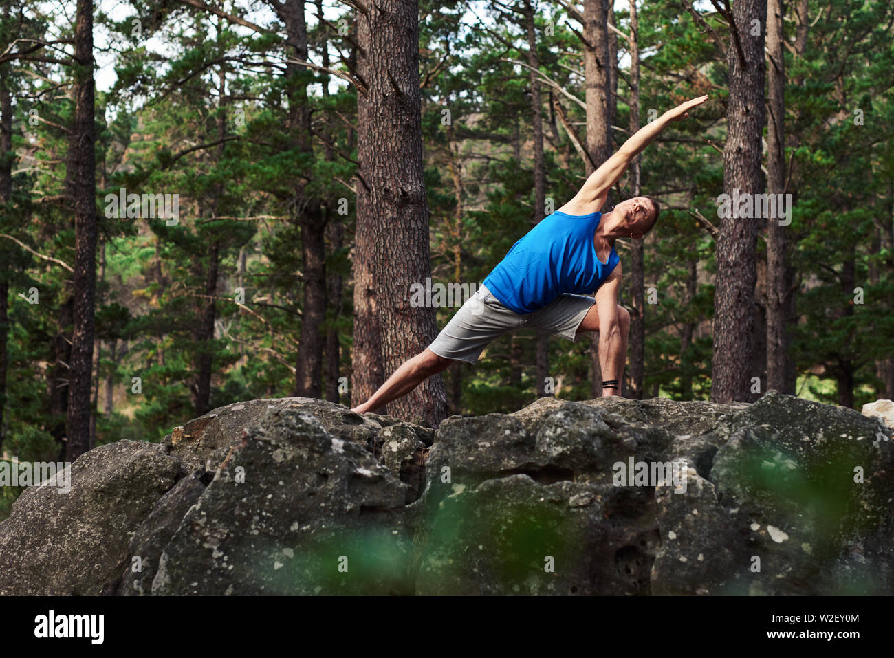 Man doing the extending side angle pose in a forest Stock Photo