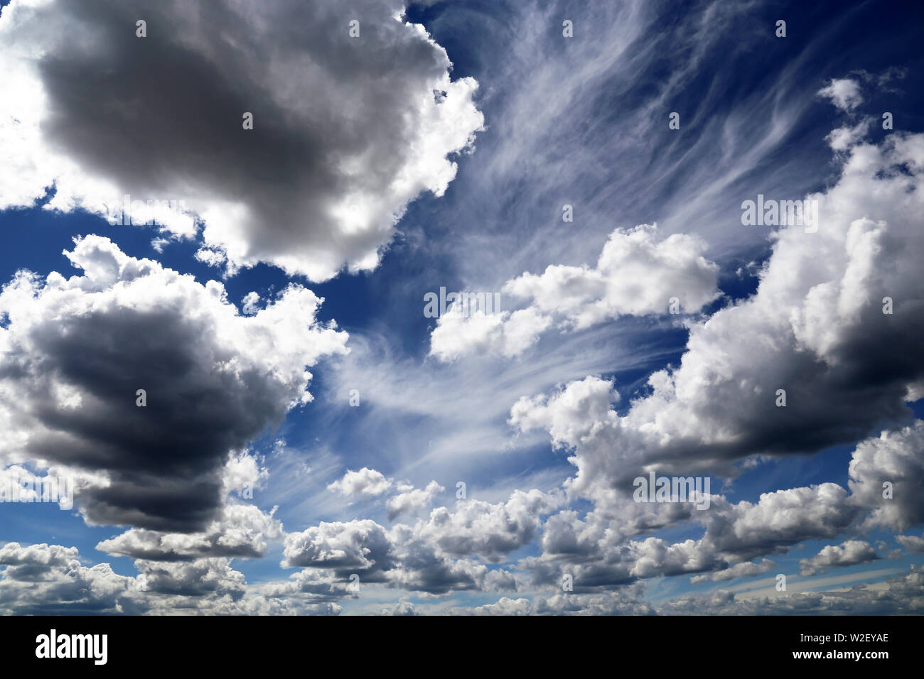 Blue sky covered with white cumulus and cirrus clouds. Summer cloudscape, beautiful background for good weather before the storm Stock Photo