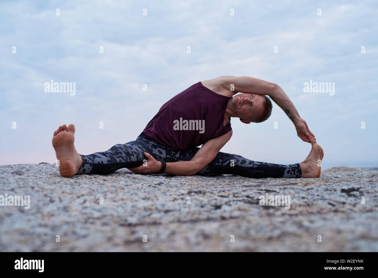 Man doing the revolved head to knee pose outdoors Stock Photo
