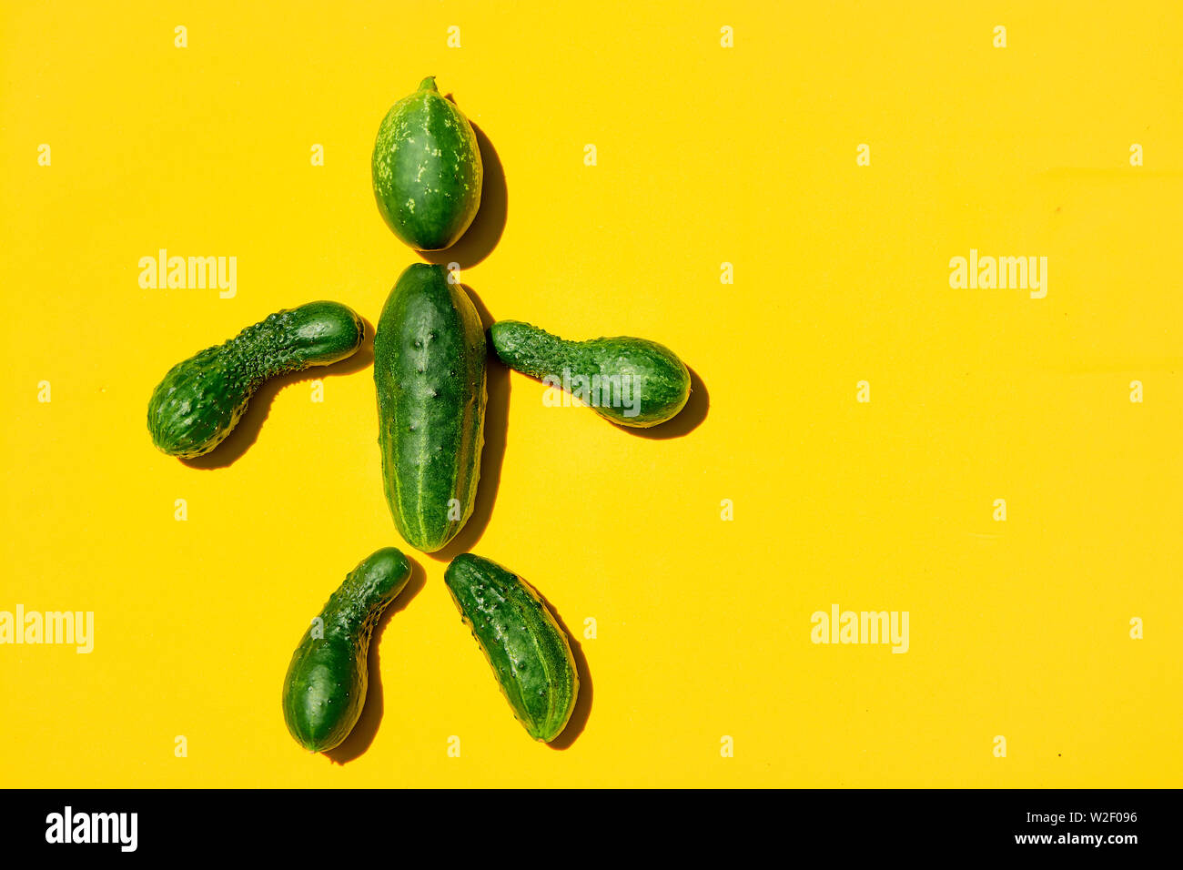 Cucumber man on a yellow background. Figure of man made from cucumbers