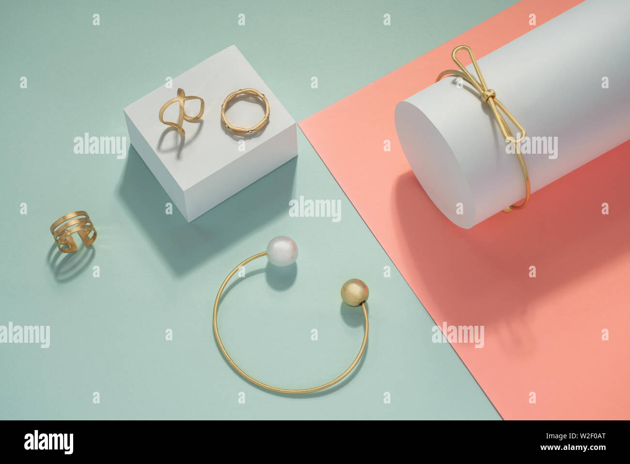Golden Accessories set bracelets and rings on pink and blue background Stock Photo