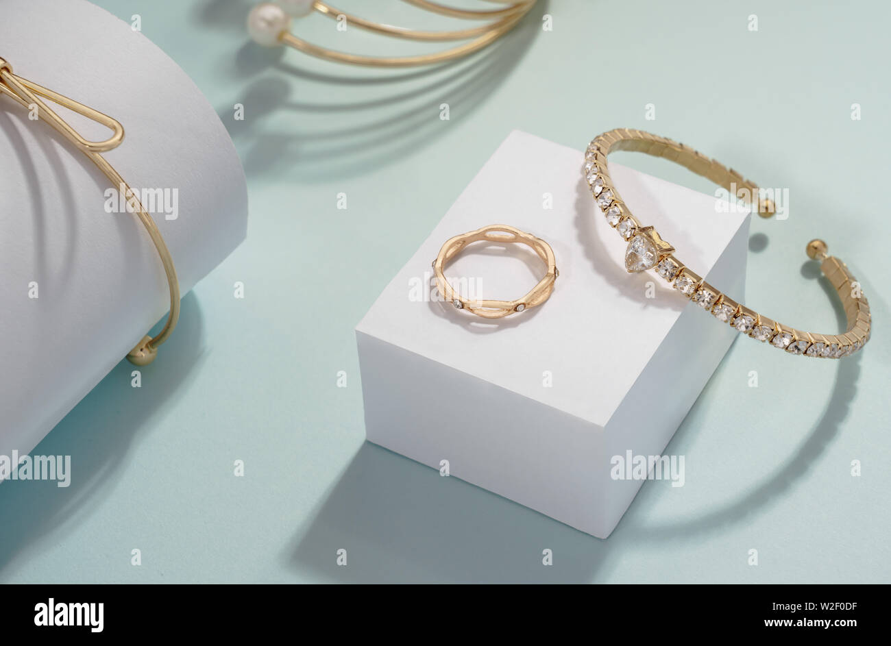 Golden bracelets set with golden ring on white cube display Stock Photo