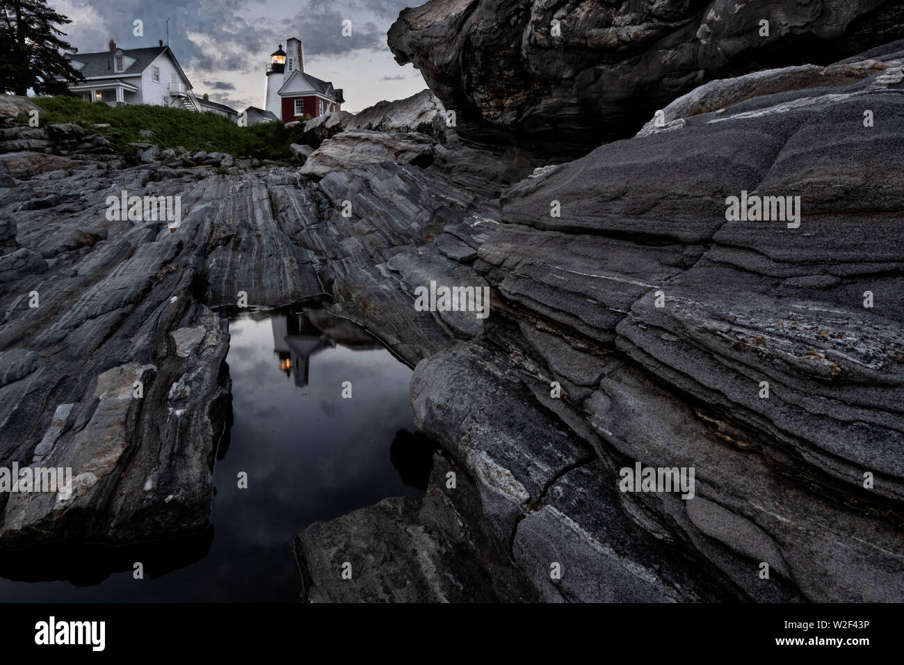 The historic Pemaquid Point Lighthouse reflected in a pool of water in the rocky landscape in Bristol, Maine. The picturesque lighthouse built along the rocky coast of Pemaquid Point was commissioned in 1827 by President John Quincy Adams. Stock Photo