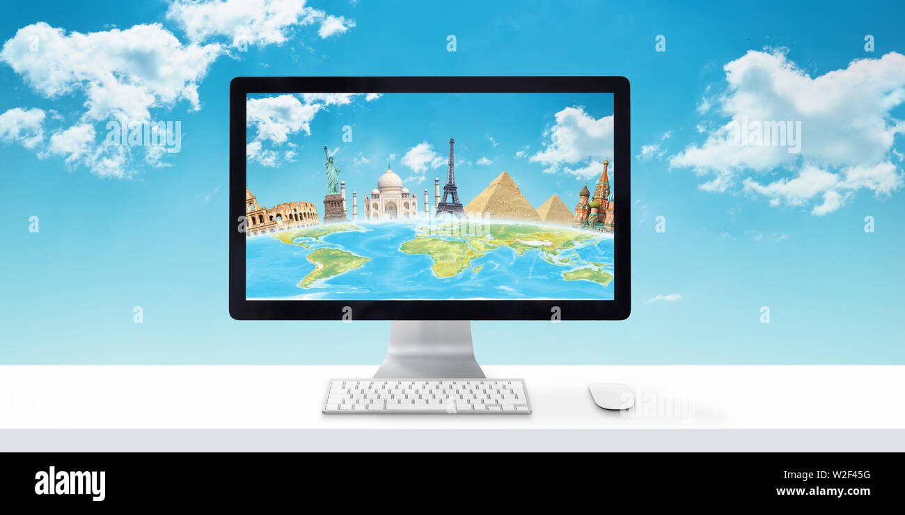 Computer display with globe and famous world sights on white desk. Concept of booking and planning holiday online. Sky and clouds in background. Stock Photo