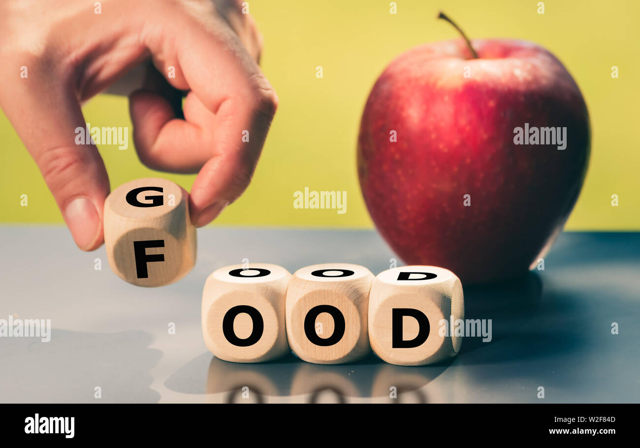 Hand turns a cube and changes the word 'good' to 'food'. Stock Photo