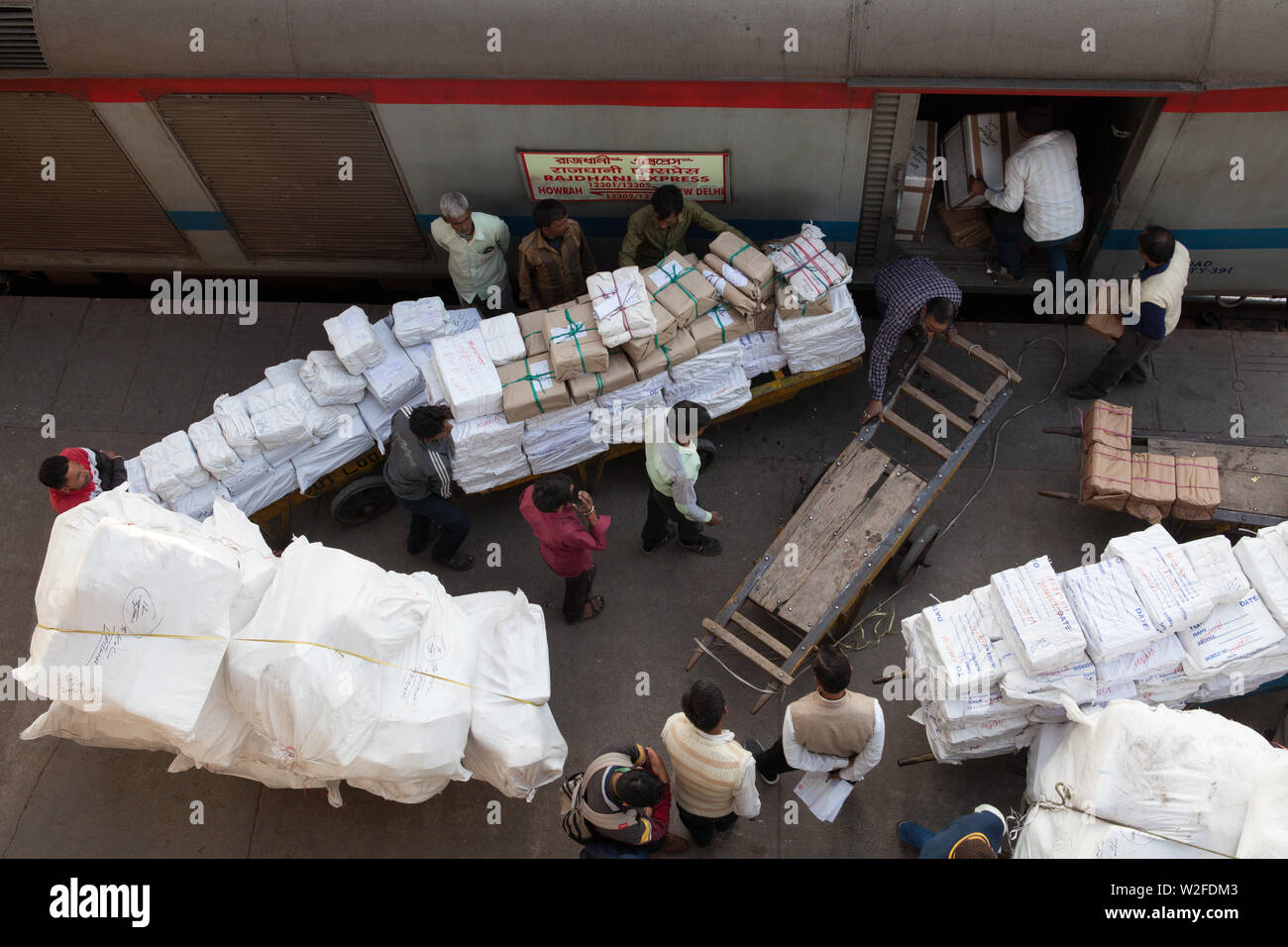 Porters load packets and parcels onto the goods carriage of a train at New Delhi railway station Stock Photo