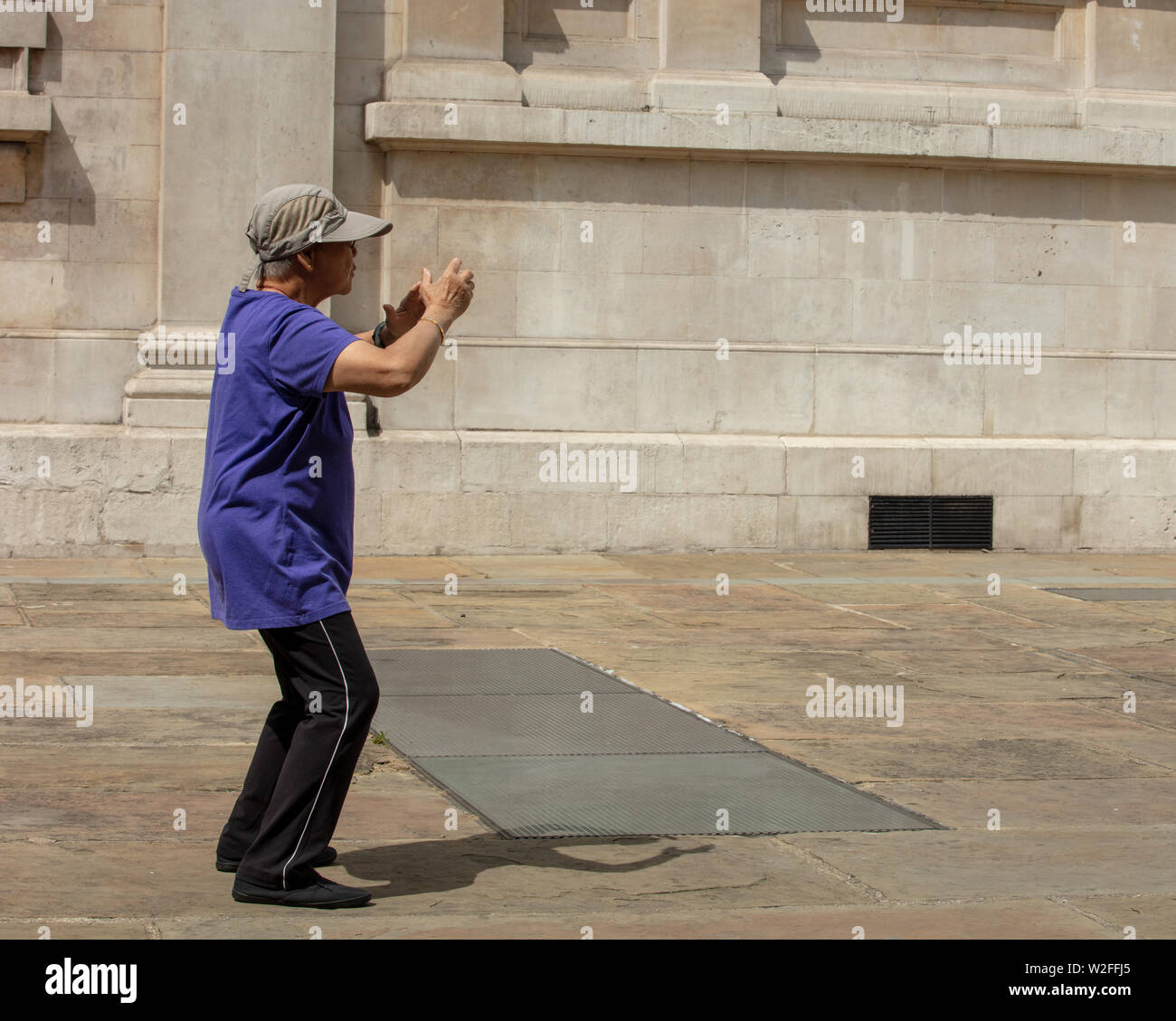 Mainly older people exercising the ancient Chinese slow moving exercise tai chi on the court behind the London church of St Martin in the Fields Stock Photo