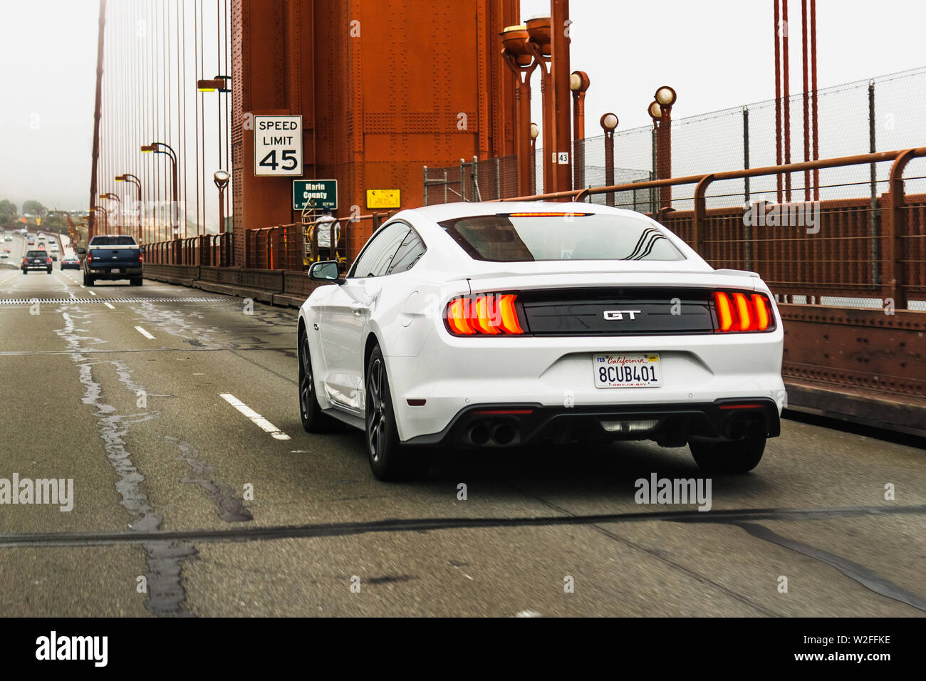 July 4, 2019 San Francisco / CA / USA - White Ford GT Mustang travelling on Golden Gate Bridge; rear view Stock Photo