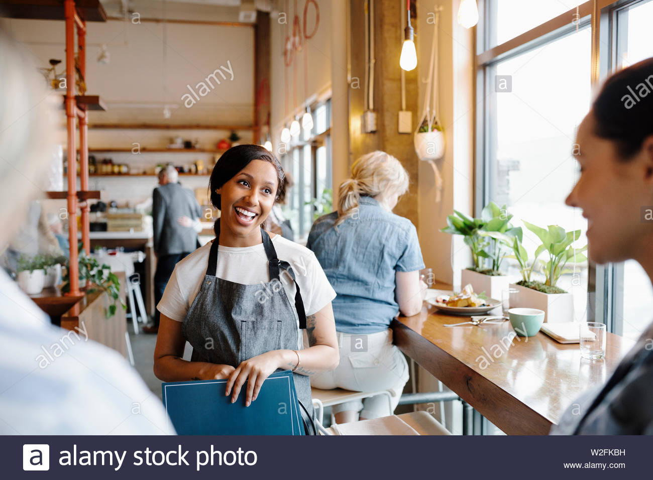 Friendly hostess greeting customers in restaurant Stock Photo Alamy