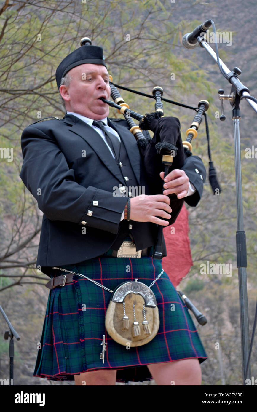 A man wearing a scottish kilt, playing the bagpipes at a festival Stock