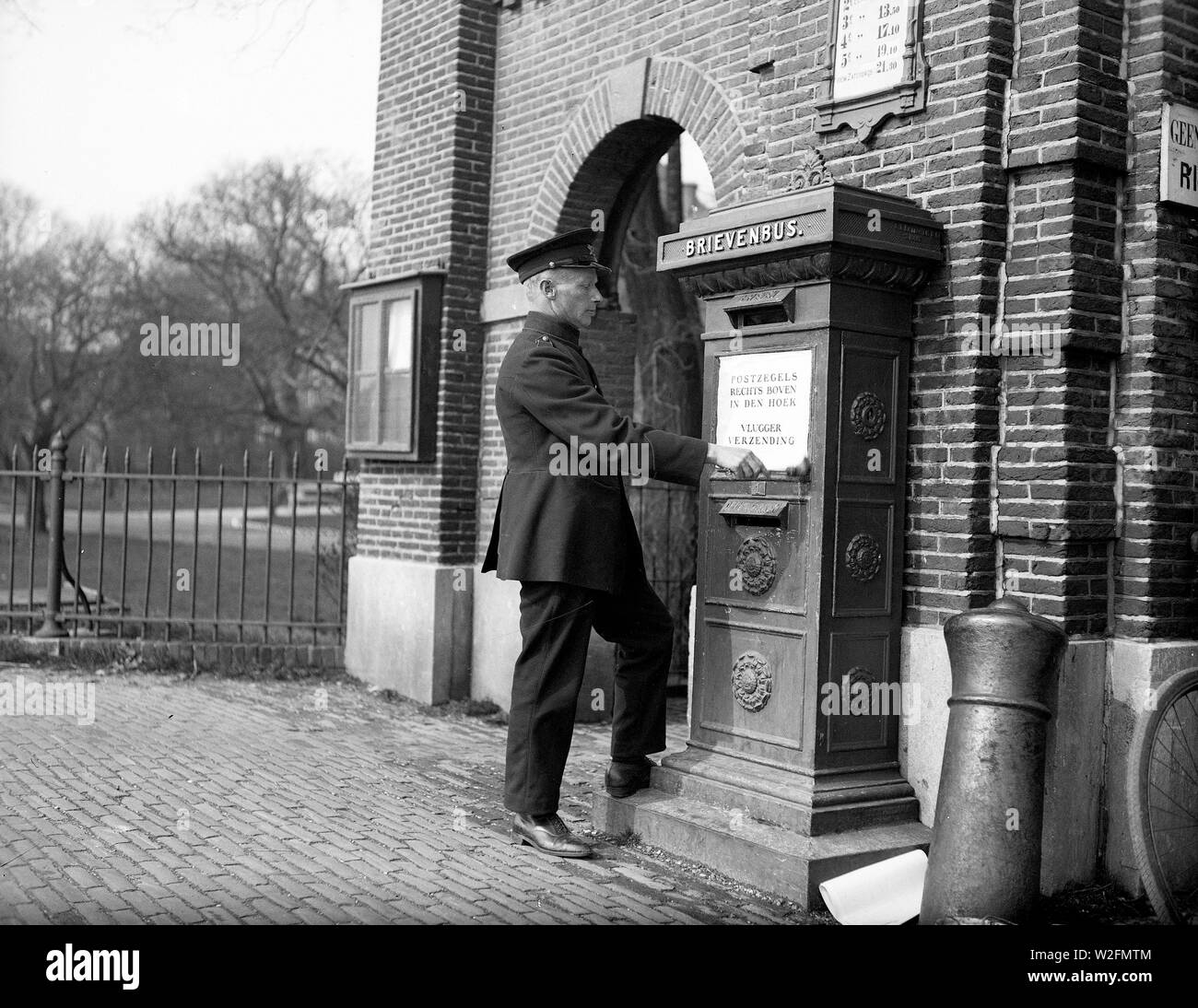 a post office worker sticks a poster on the letterbox 'Postage stamps in the upper right corner in the corner quicker shipping' Stock Photo