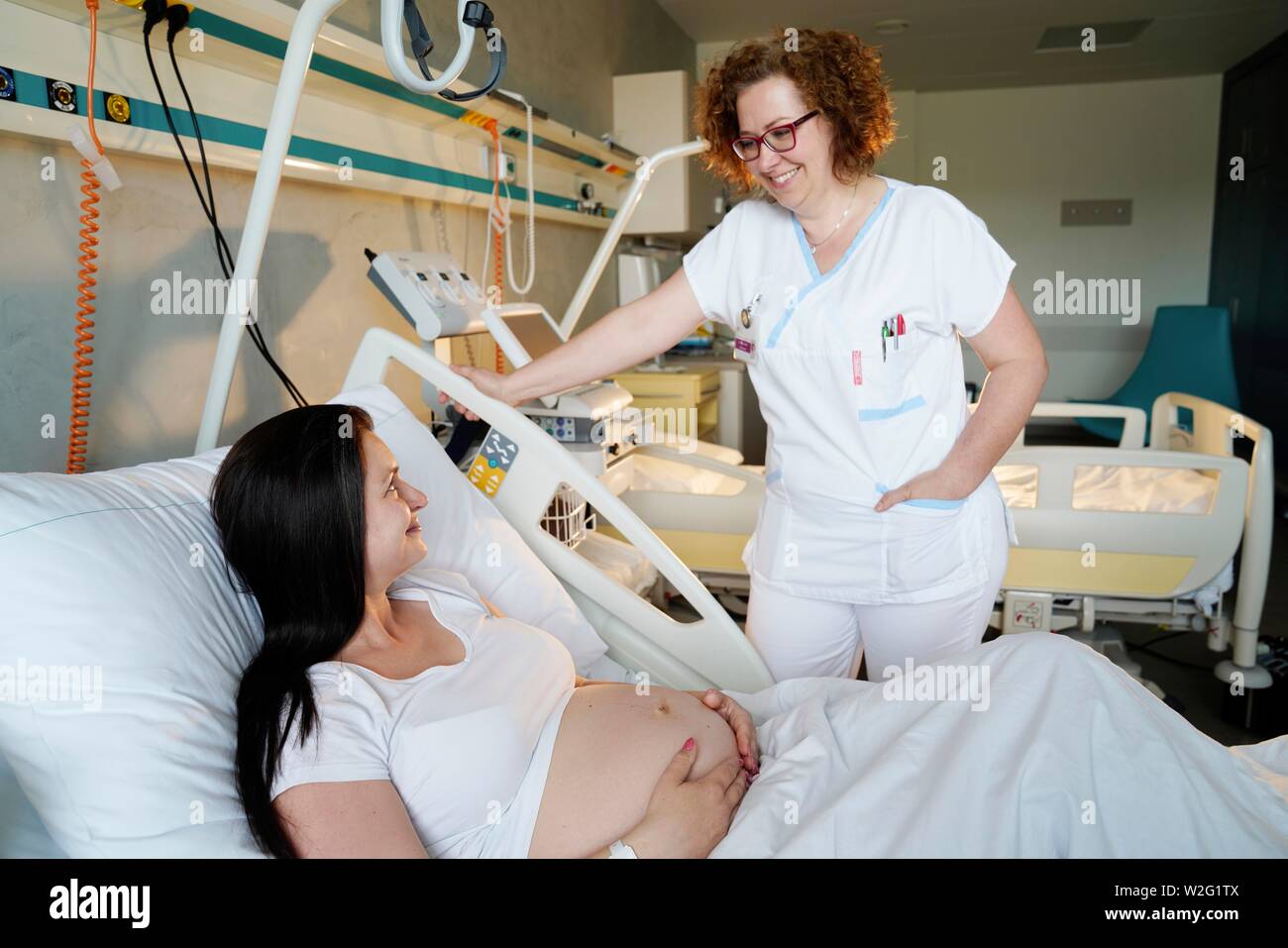 Nurse with patient, pregnant woman in bed talking in hospital room, Karlovy Vary, Czech Republic Stock Photo