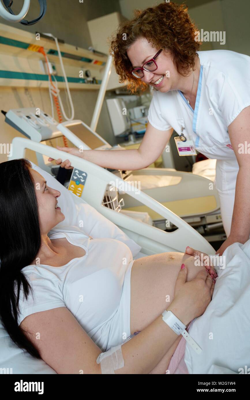 Nurse with patient, pregnant woman in bed talking in hospital room, Karlovy Vary, Czech Republic Stock Photo