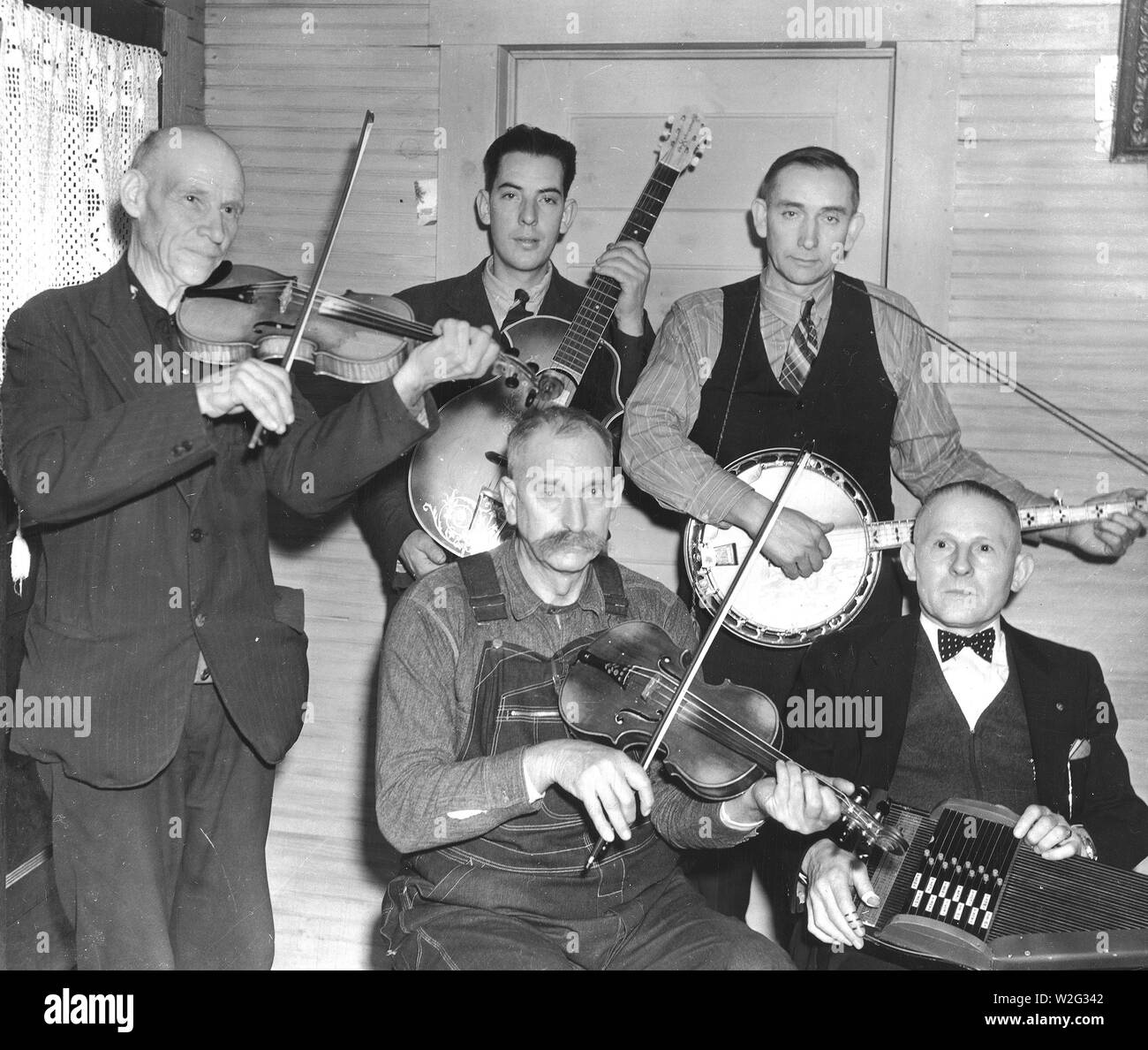 Members of the Bog Trotters Band, posed holding their instruments, Galax, Va. Back row: Uncle Alex Dunford, fiddle; Fields Ward, guitar; Wade Ward, banjo. Front row: Crockett Ward, fiddle; Doc Davis, autoharp Stock Photo