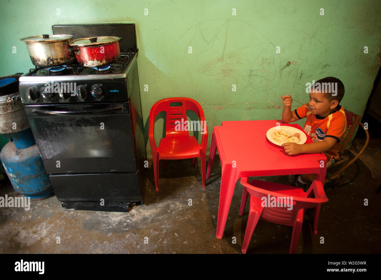 A boy eats lunch in her home's kitchen in Los Erasos shanty neighborhood in Caracas, Venezuela, July 22, 2008. Gladys lives with her sisters Emperatri Stock Photo