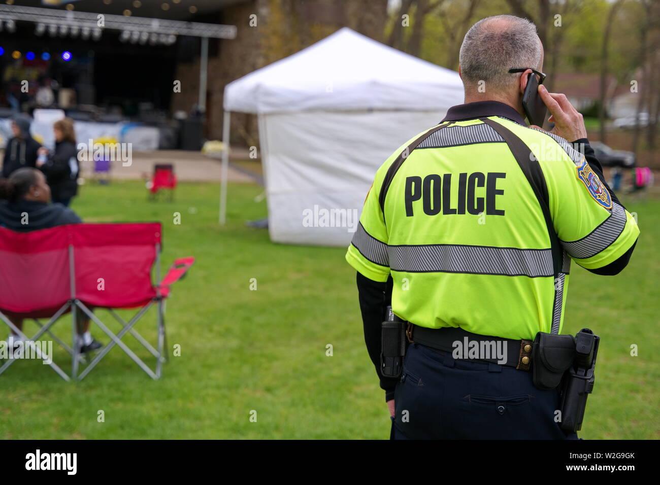Meriden, CT USA. Apr 2019. Daffodil Festival. Police officer on phone vigilant around the festival grounds. Stock Photo