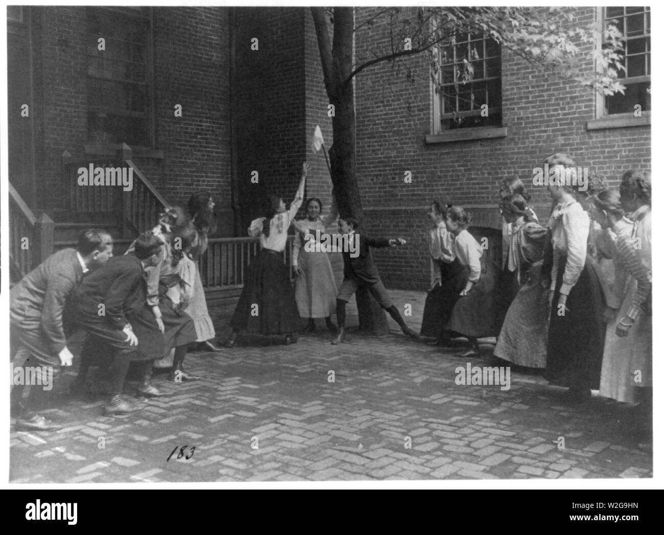 Children playing game with handkerchief on stick in school yard