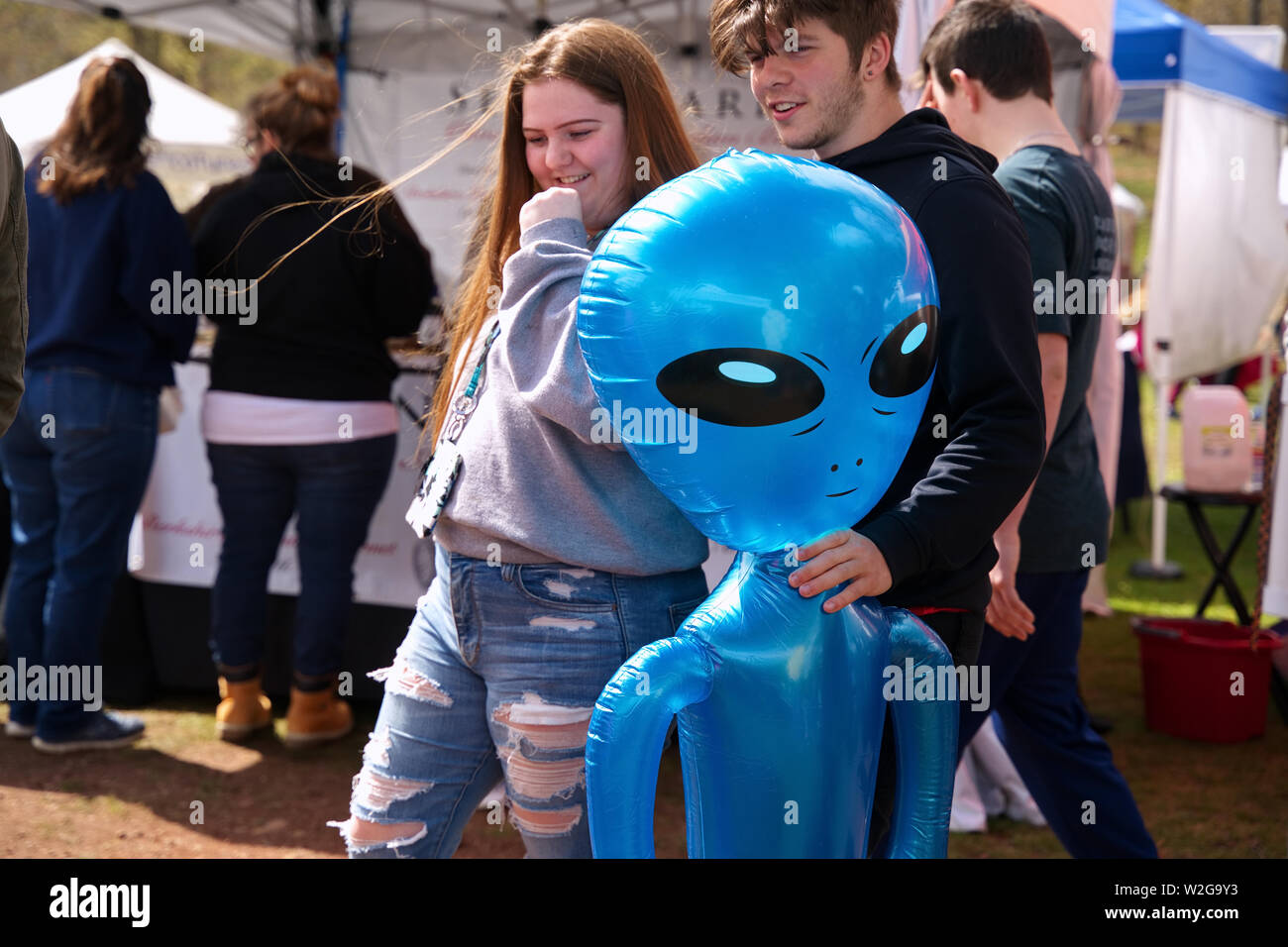 Meriden, CT USA. Apr 2019. Daffodil Festival. Couple holding an alien inflatable hostage. Stock Photo