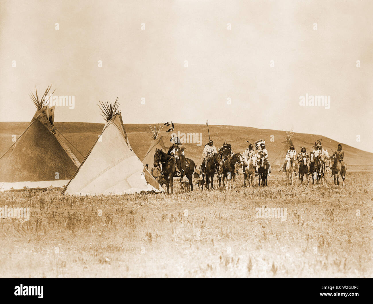 Landscape with four tepees, eleven Atsina Indians on horseback, three women, a child, and two dogs, Montana Stock Photo
