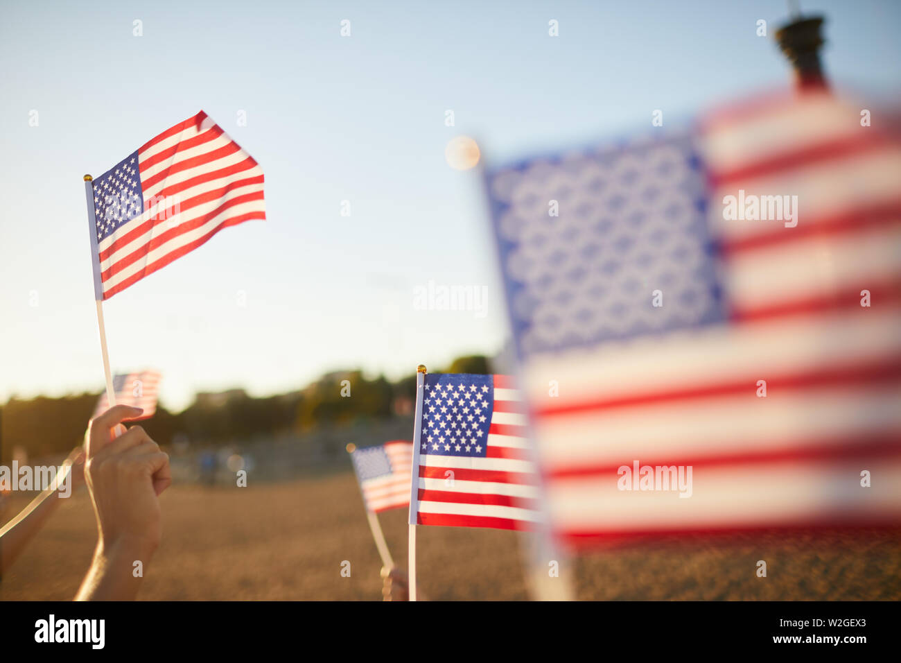 Crowd of unrecognizable people holding US stick flags while preserving memory of American heroes Stock Photo