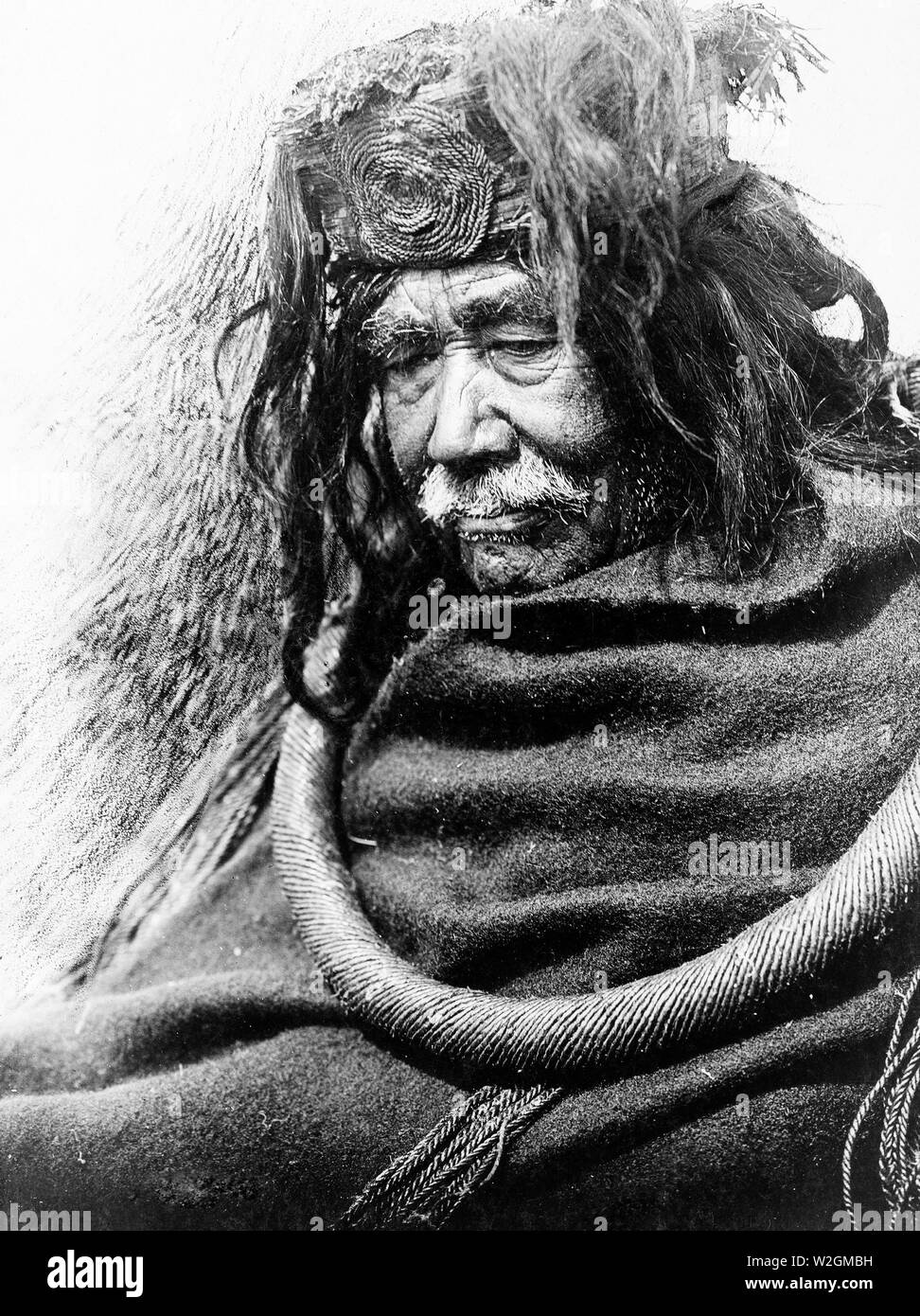 Edward S. Curits Native American Indians - Half-length portrait of Nakoaktok man, facing left, wearing cedar root ceremonial loop ca. 1910 Stock Photo