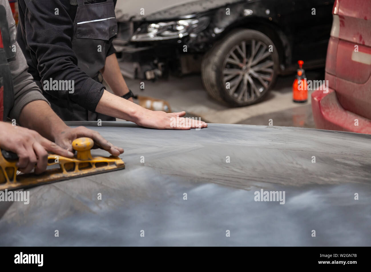 Preparation for painting a car element using emery sender by a service technician leveling out