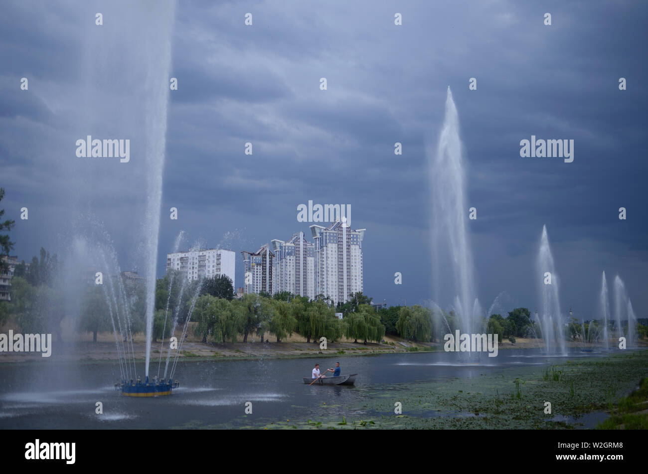 Evening view of the Rusanovka canal, men rowing boat, fountains working. June 5, 2019. Kiev, Ukraine Stock Photo