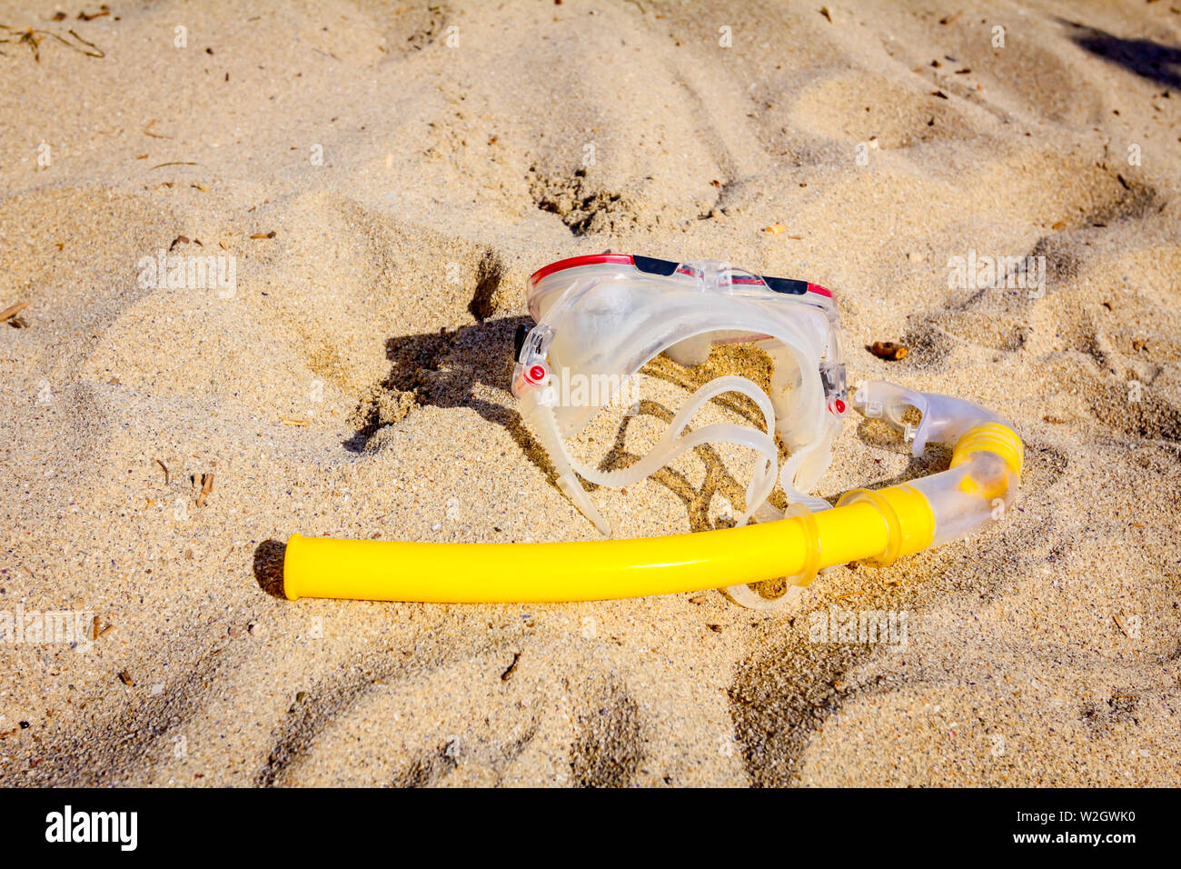 Diving mask and snorkel breather tube are placed on the sandy beach