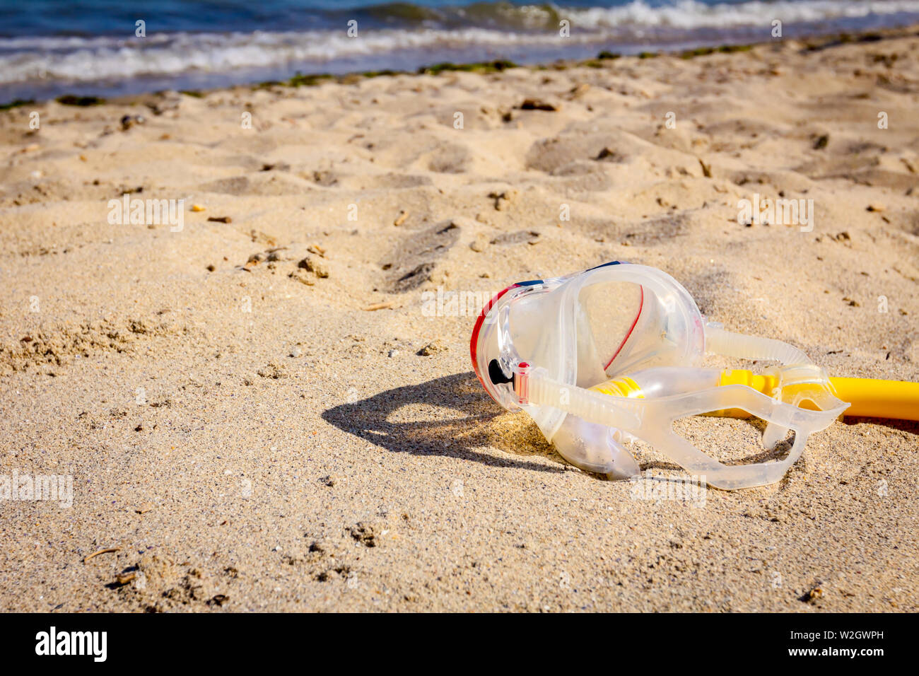 Diving mask and snorkel breather tube are placed on the sandy beach