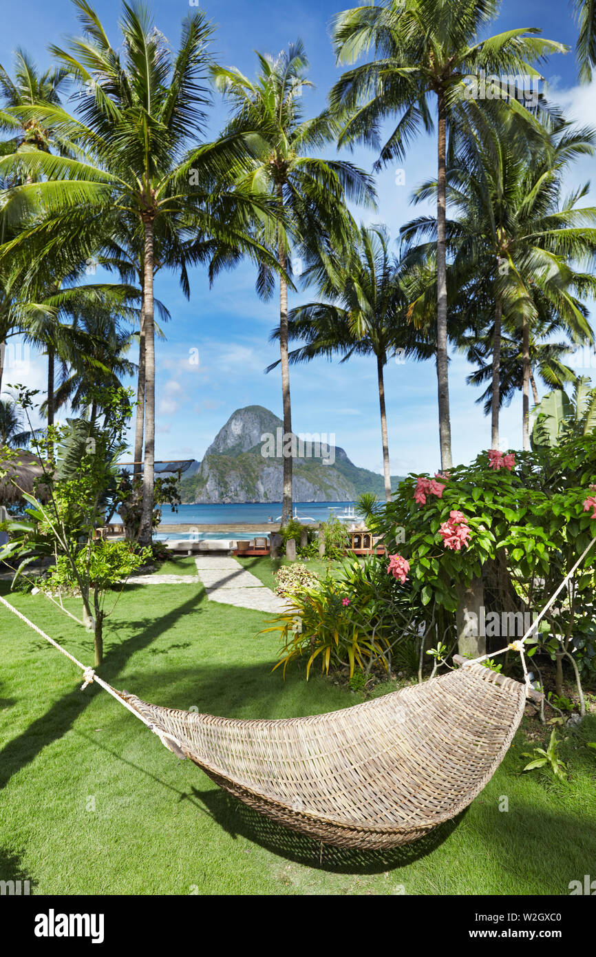 Tropical garden in front of the sea, hammock between a palm trees, El-Nido, Philippines Stock Photo
