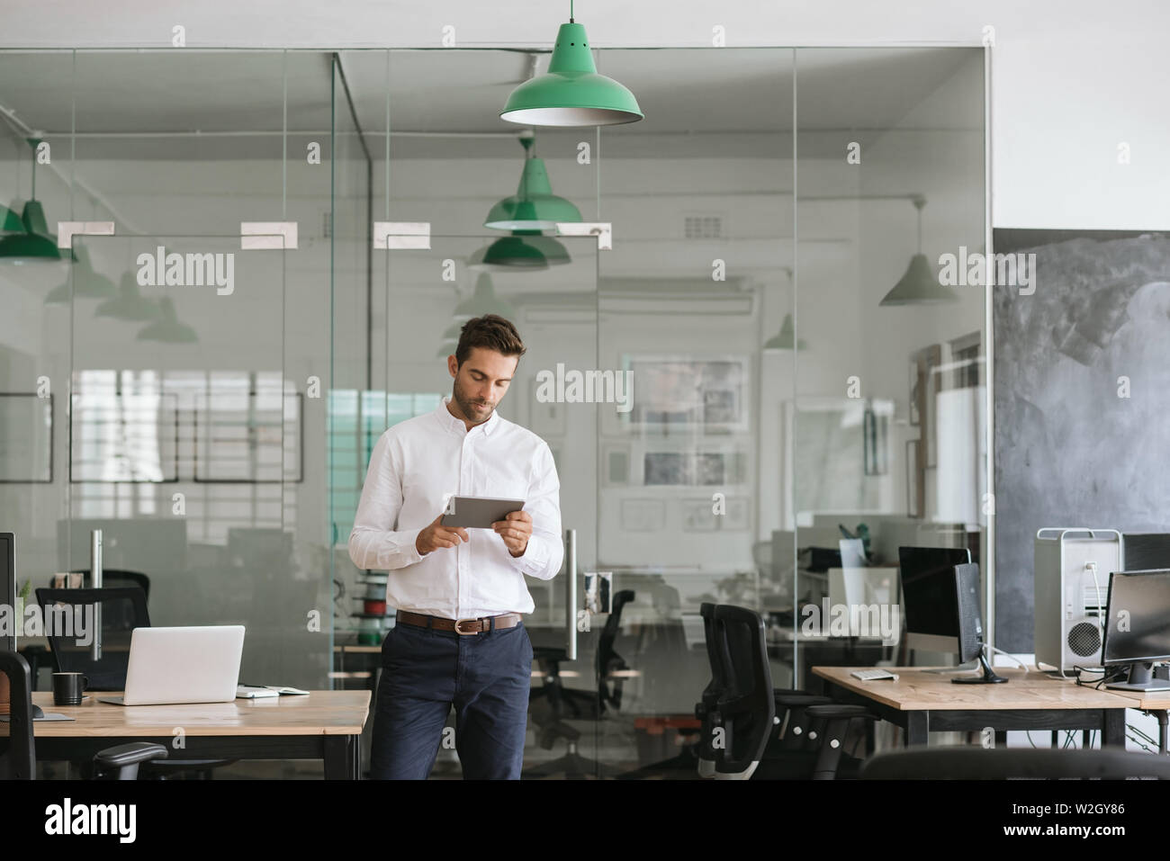 Young businessman using a tablet while standing in an office Stock Photo