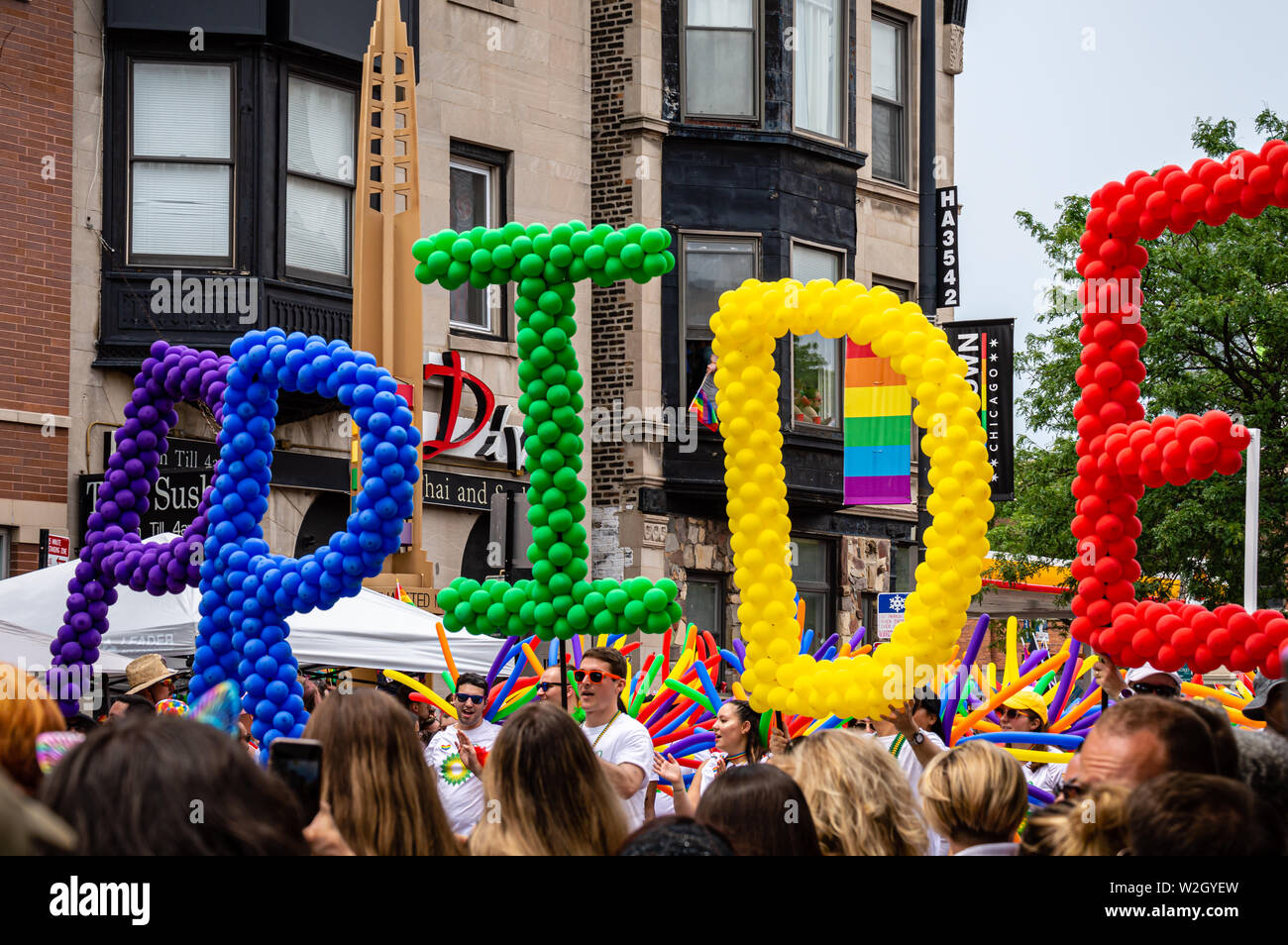 Lakeview, Chicago-June 30, 2019: People marching with rainbow color balloons that spell the word 'Pride.' Stock Photo