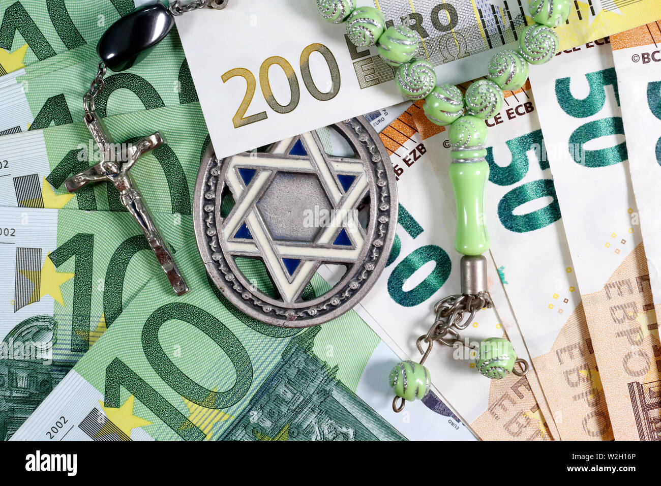 Banknotes of euro currency.  Christianity, Islamic and Judaism finance and economy concept with Jewish Star, Prayer Beads and Crucifix. Interreligious Stock Photo