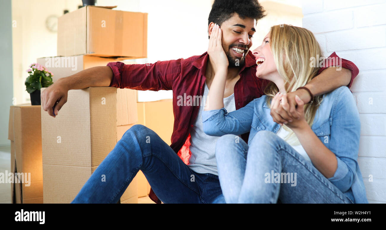 home, people, moving and real estate concept - happy couple having fun while moving in Stock Photo