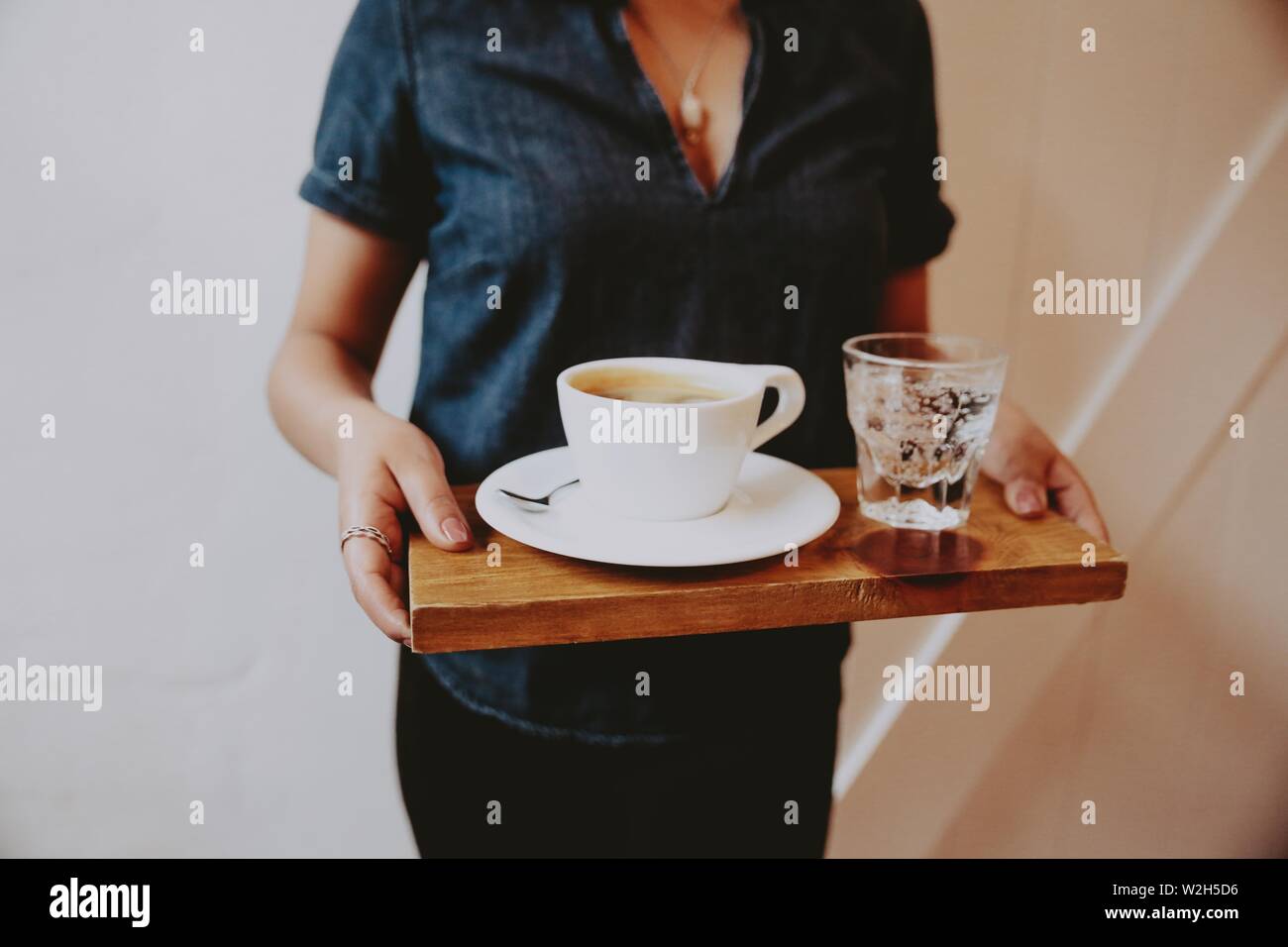 https://c8.alamy.com/comp/W2H5D6/female-in-a-low-cut-shirt-holding-a-wooden-tray-with-coffee-and-sparkling-water-on-it-W2H5D6.jpg