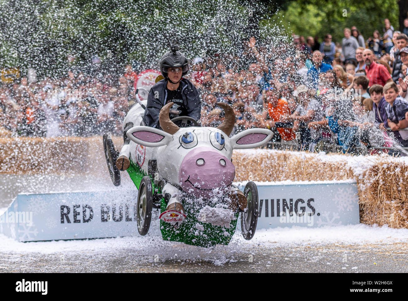 Driving Miss Daisy cow cart competing in the Red Bull Soapbox Race 2019 at Alexandra Park, London, UK. Jumping over ramp with people Stock Photo