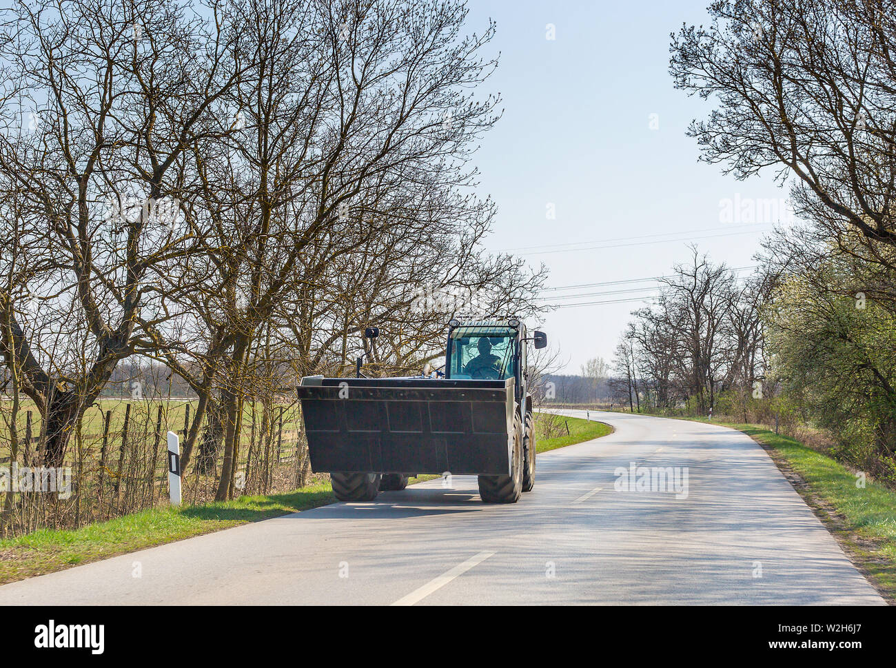 Excavator moves on asphalt road in spring Stock Photo