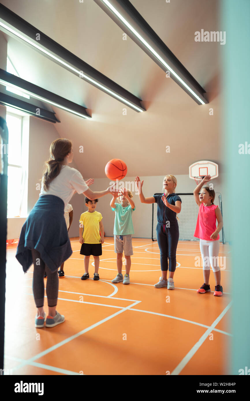 Sports teacher throwing ball to her pupils Stock Photo Alamy