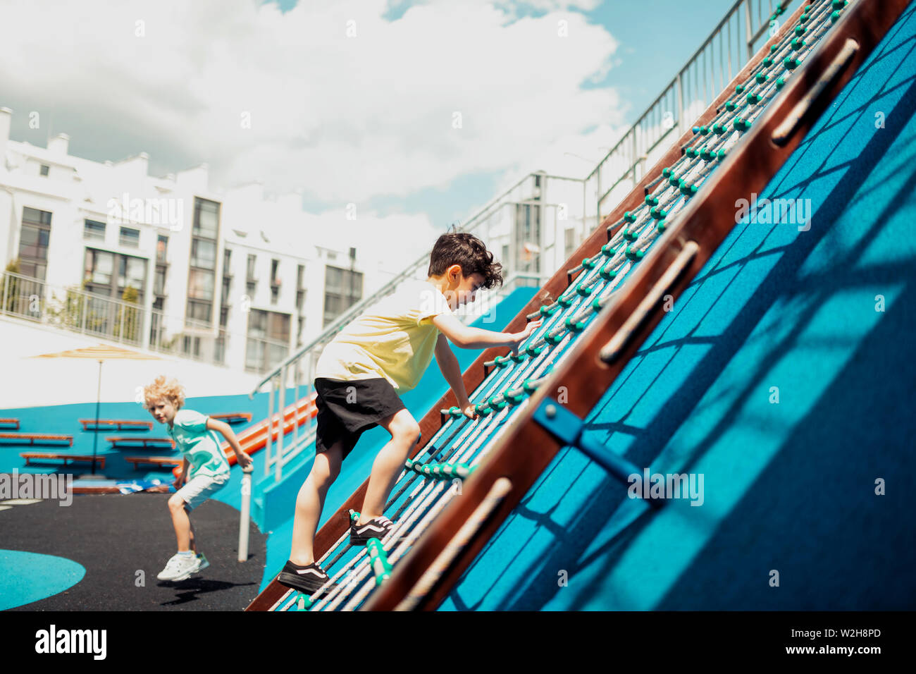 Schoolboy climbing a rope ladder on a sports ground Stock Photo Alamy