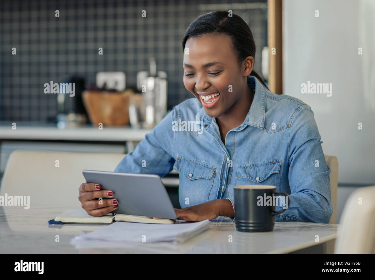 Laughing African American woman using a digital tablet at home Stock ...