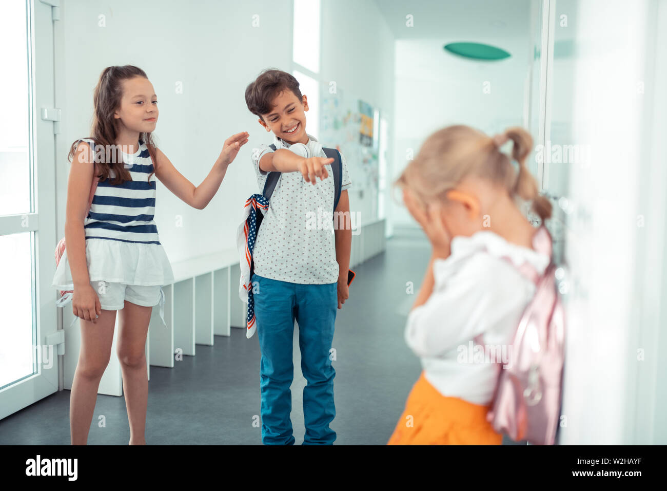 Rude boy and girl laughing at little blonde girl Stock Photo