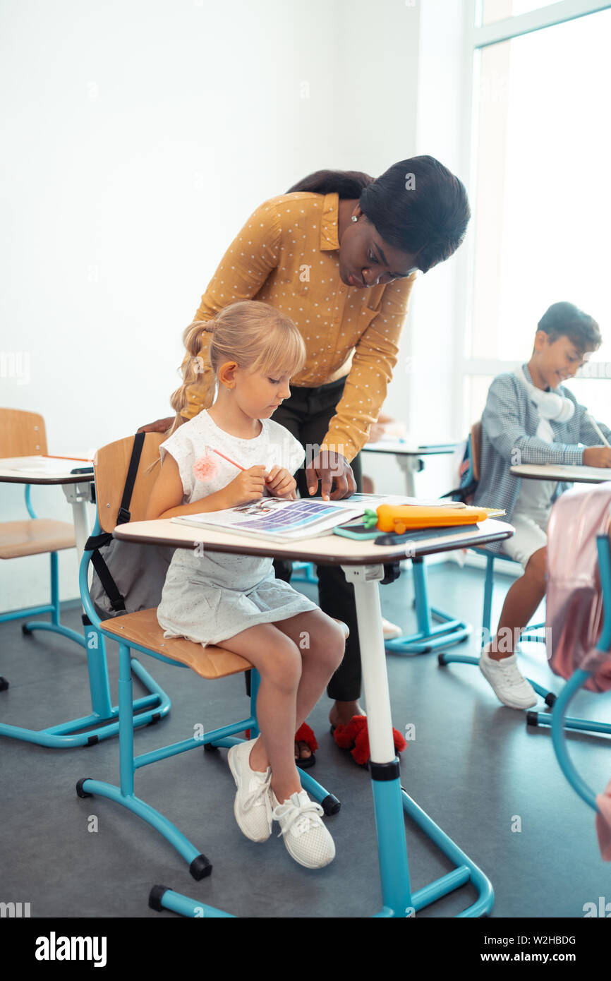 Diligent blonde-haired girl listening to teacher attentively Stock Photo