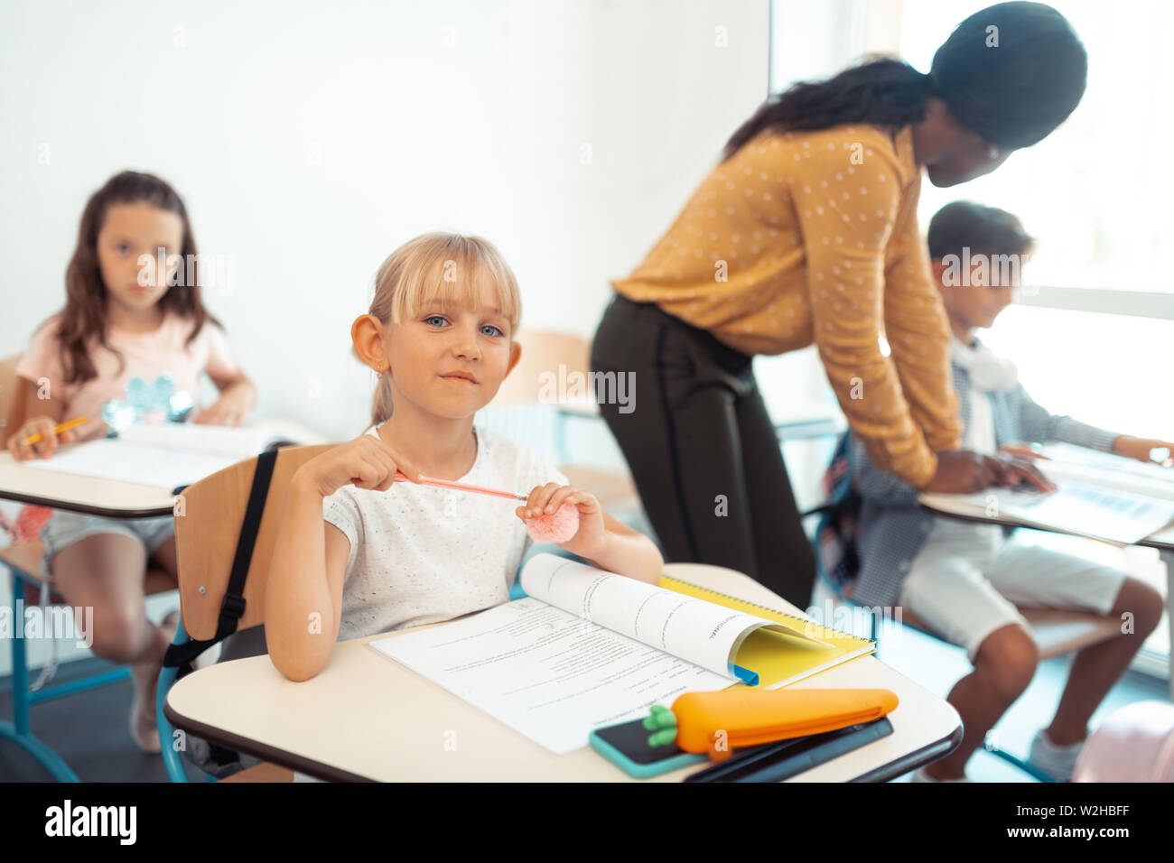 Beautiful blue-eyed schoolgirl sitting at the desk in classroom Stock ...